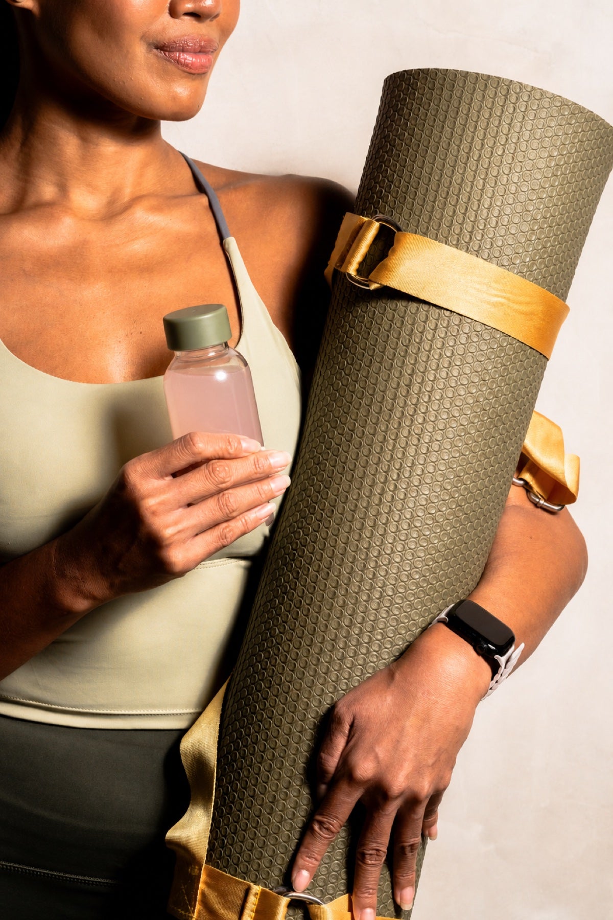 The Calm Plus female campaign model holding her yoga mat and a reusable bottle of guava drink after her workout